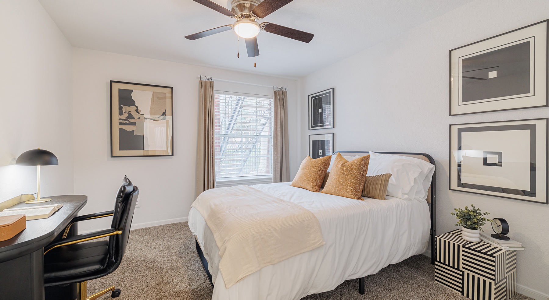 bedroom with bed ceiling fan desk chair and art on the wall