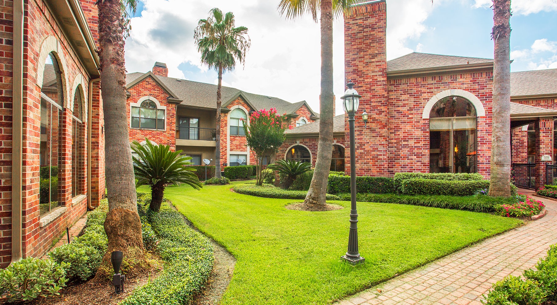 a courtyard with green grass and palm trees