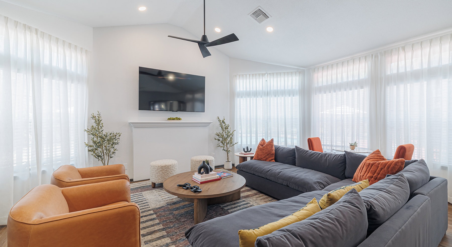 lounge with seating ceiling fan and tv