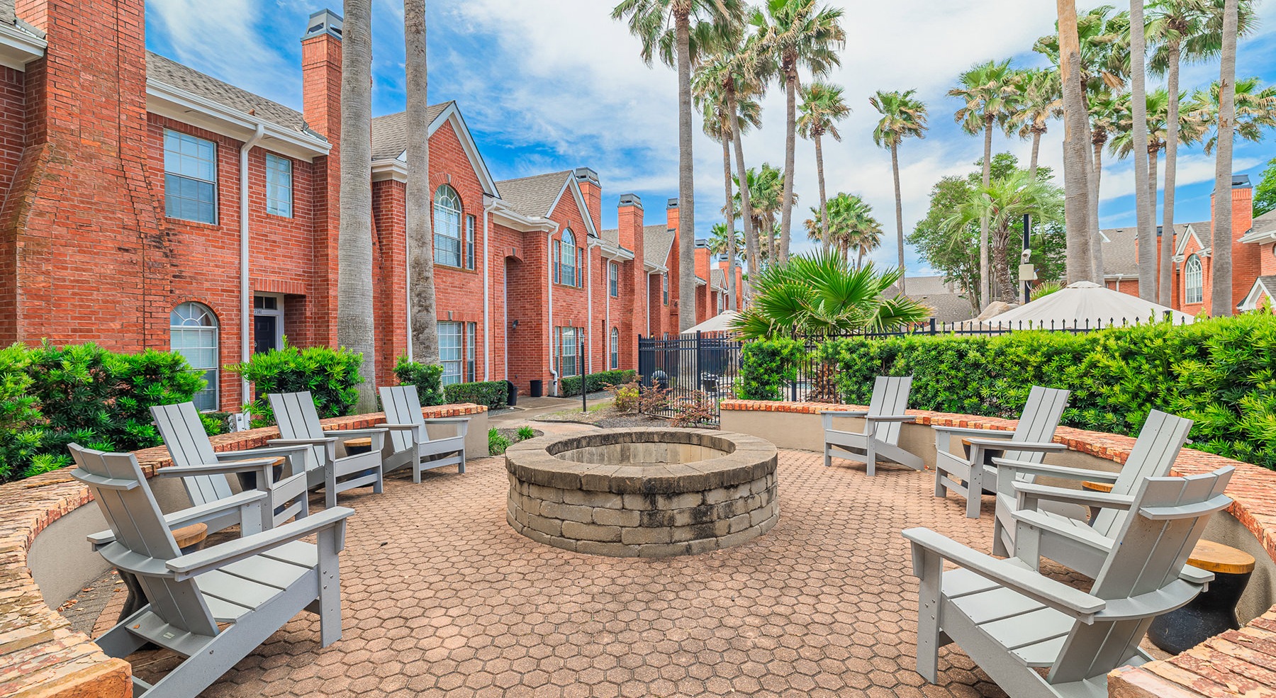 a fire pit with seating around it and palm trees